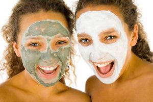 Happy young women with masks anti-aging. They're on white background. Front view